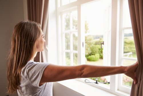 En kvinde kigger ud af vinduet efter at slippe af med lugten af fugt