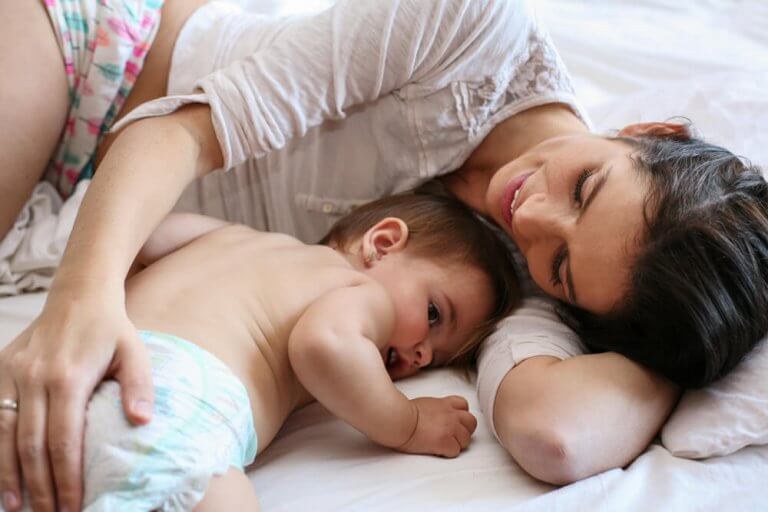 Enlig mor ligger ved siden af baby