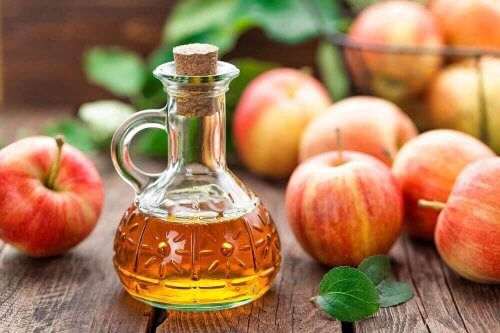 Æblecidereddike i glasflaske med æbler omkring