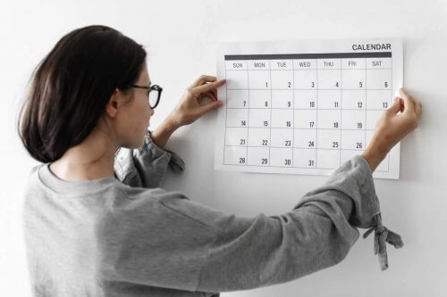 En kvinde sætter en kalender på væggen.