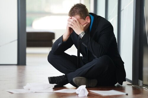Mand på gulv på kontor er plaget af at arbejde for meget