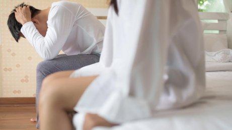 En mand sidder på sengen og tager sig til hovedet