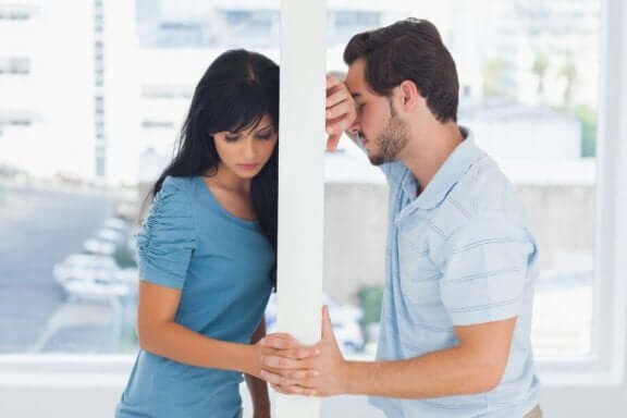 Mand og kvinde på hver side af væg holder i hånd, hvilket illustrerer, at en eks vil være venner