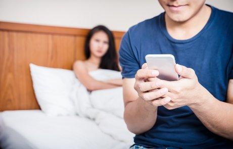 Jaloux kvinde kigger på mand med telefon