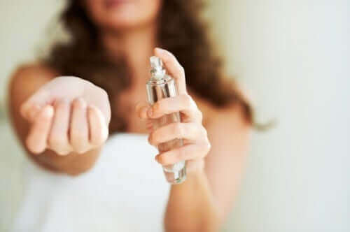 Kvinde sprøjter parfume på hånden