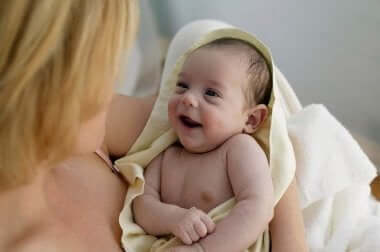 Mor krammer smilende baby i håndklæde