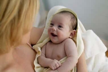 Mor krammer smilende baby i håndklæde