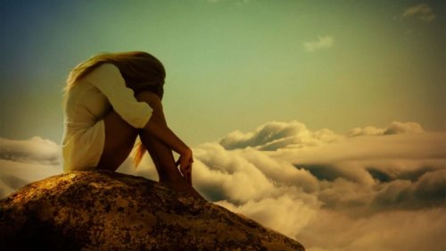 Kvinde, der sidder og er ensom på bjergtop