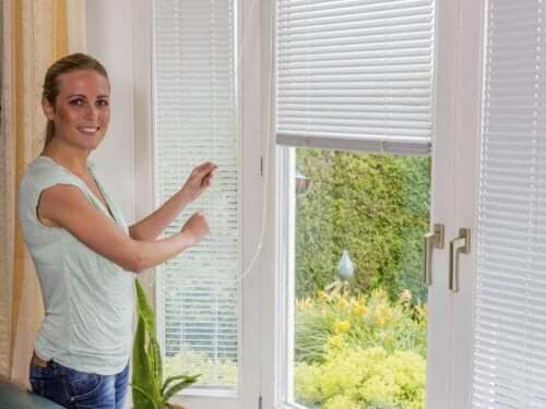 Kvinde ved persienner smiler