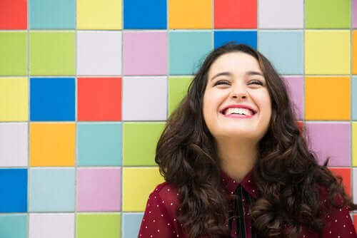 En smilende kvinde foran farverig væg