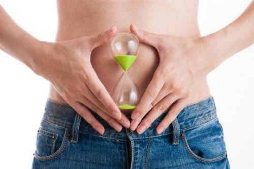 Kvinde holder timeglas foran maven