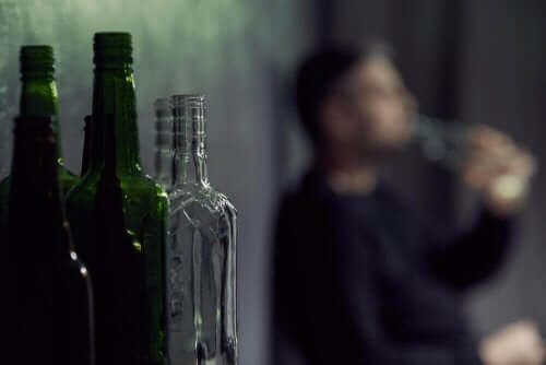 Mand med alkoholproblem ses sløret bag tomme flasker