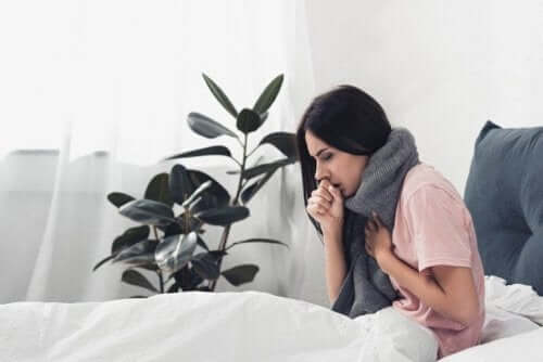 Kvinde i seng oplever feber og kropssmerter, som er en af de største forskelle mellem forkølelse og influenza