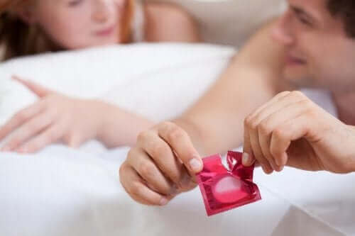 Par i seng, hvor mand åbner kondom