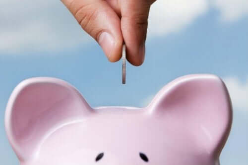 Person kommer mønt i sparegris