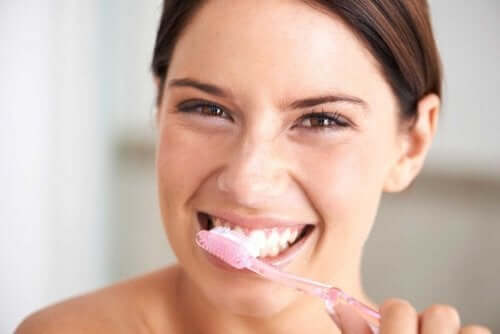 Kvinde børster tænder med produkter til at blege tænder