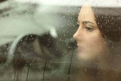 Kvinde i bil ser ud af vindue med regn på