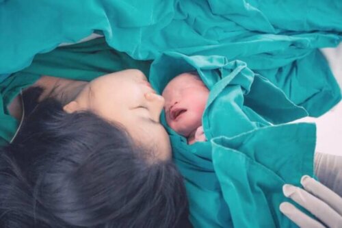 Nyfødt baby med sin mor, der har oplevet bristning under fødsel
