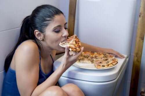 Kvinde spiser pizza på toilet