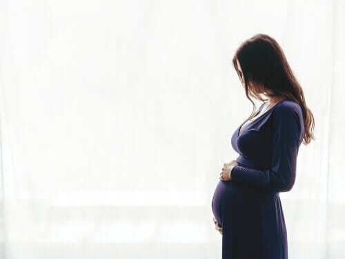 Gravid kvinde foran hvid væg
