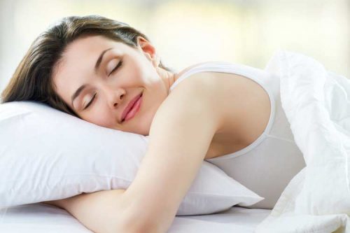 Smilende kvinde ligger i seng