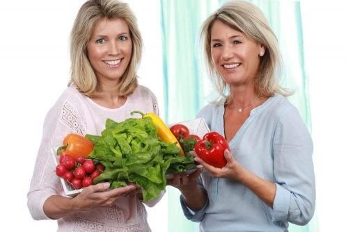 To kvinder holder en masse grøntsager 