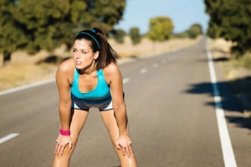 Kvinde, der stopper op på løbetur, tænker over sammenhængen mellem mælkesyre og motion