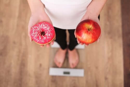 Person holder æble og donut i hænderne