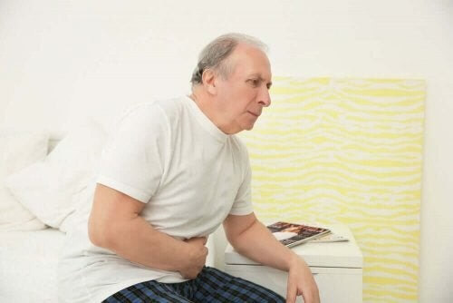 Ældre mand sidder på kanten af sengen med smerter 