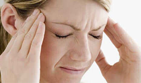 Kvinde med hovedpine tager sig til hoved