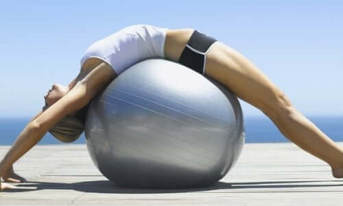 Kvinde på stor bold dyrker pilates