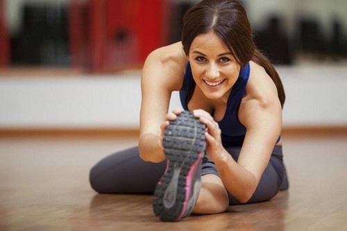 Kvinde laver strækøvelser på gulvet