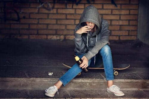Person med cigaret i munden sidder på skateboard