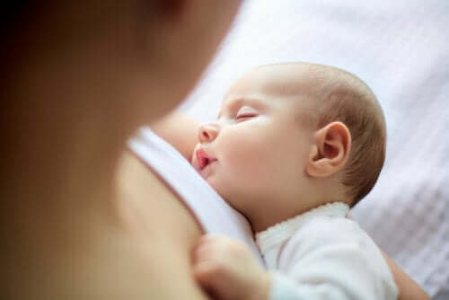 Baby sover på mors arm 