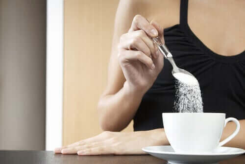 Dårlige fødevarer for led: En kvinde, der tilsætter sukker til sin te