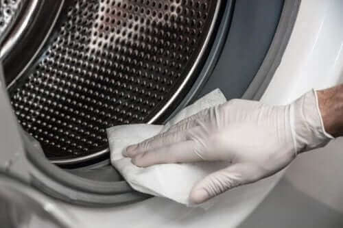 En person, der rengør vaskemaskine, for at slippe af med den mugne lugt i tøj