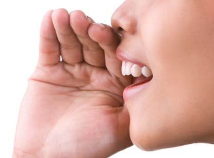 Pige smiler med hånden ved munden