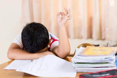 Træthed eller udmattelse kan være et symptom på anæmi hos børn, som det her illustreres af dreng, der hviler hoved på bord