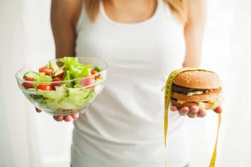 Kvinde holder burger og salat i hænderne