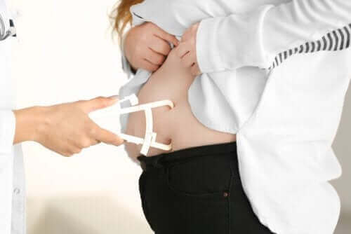 Læge måler persons mavefedt som del af at forebygge fedme