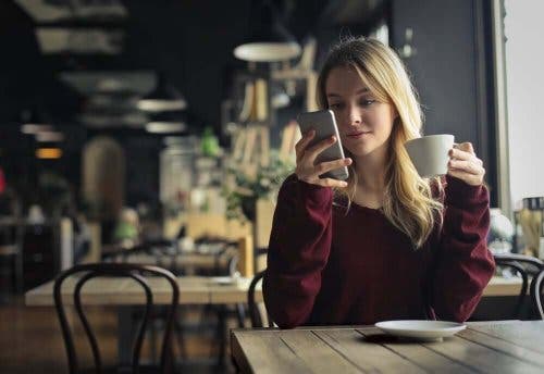 Kvinde på café sidder med sin telefon
