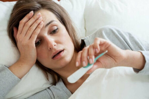 Kvinde i seng med termometer i hånden har Q-feber
