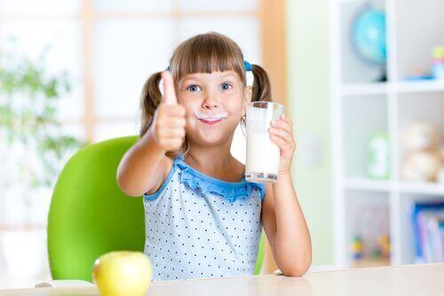 Pige med mælkeskæg og et glas mælk i hånden