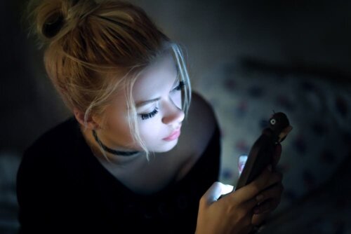 Kvinde ser på telefon i mørke