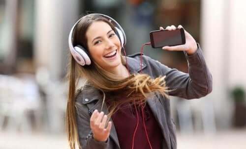 Smilende kvinde lytter til musik i høretelefoner