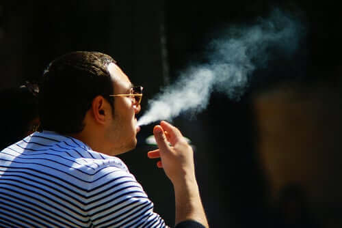 Mand sidder og ryger, selvom tobak påvirker huden
