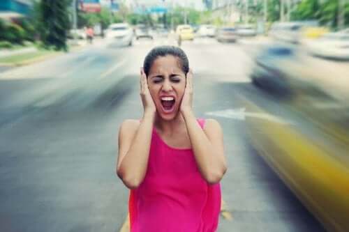 Kvinde på vej holder sig for ørerne, da støj påvirker humøret