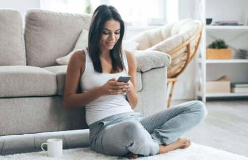 Kvinde sidder med telefon i hånden