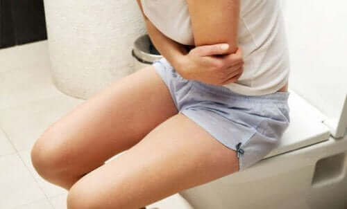 Kvinde på toilet har ondt i maven grundet kronisk forstoppelse