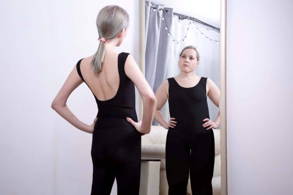 Slank kvinde ser sig selv som overvægtig i spejl grundet sadomasochistisk anoreksi